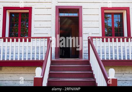 Eingangstreppe eines traditionellen Holzhauses in Nordamerika. Weiß mit rotem Geländer am Weißen Haus. Die Treppe führt nach oben. Detail einer hölzernen Veranda Stockfoto