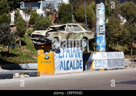 Autounfall auf einem Sockel mitten auf der Autobahn als Warnung an die Fahrer, nicht zu trinken, fahren und vorsichtig fahren, La Ceja, El Alto, Bolivien Stockfoto