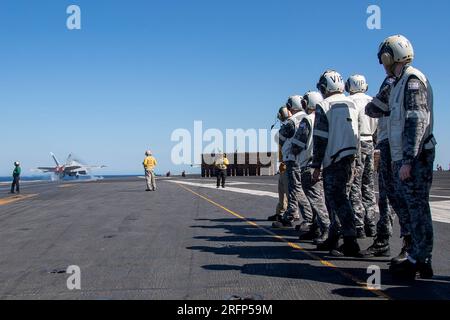 INDISCHER OZEAN (4. August 2023) Royal Australian Navy (RAN) Matrosen, die der RANNTEN Fregatte HMAS Perth (FFG 157) zugeteilt sind, beobachten, wie ein F/A-18F Super Hornet, das an den Diamondbacks of Strike Fighter Squadron (VFA) 102 befestigt ist, vom Flugdeck der USA startet Der einzige vorwärtsgesetzte Flugzeugträger der Navy, USS Ronald Reagan (CVN 76), während einer Schifffahrt im Indischen Ozean am 4. August 2023. Ronald Reagan, das Flaggschiff der Carrier Strike Group 5, stellt eine kampfbereite Truppe bereit, die die Vereinigten Staaten schützt und verteidigt und Bündnisse, Partnerschaften und kollektive maritime Interessen in der Indo unterstützt Stockfoto