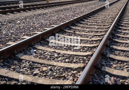 Nahaufnahme von rostigen Eisenbahnschienen mit Schottersteinen Stockfoto