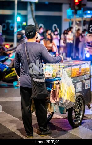 Ein thailändischer Obstverkäufer macht sich auf den Weg entlang der Silom Road In der geschäftigen Innenstadt von Silom, Bangkok City, Thailand. Stockfoto