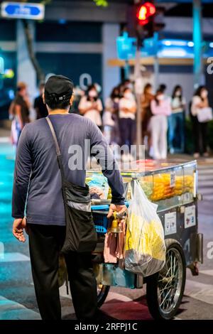 Ein thailändischer Obstverkäufer macht sich auf den Weg entlang der Silom Road In der geschäftigen Innenstadt von Silom, Bangkok City, Thailand. Stockfoto