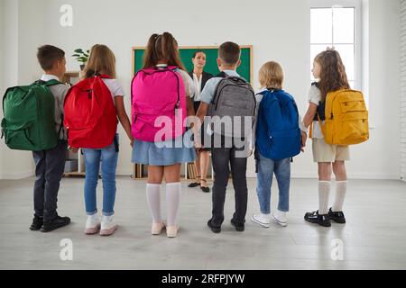 Gruppe von Klassenkameraden, die vor dem Unterricht oder am ersten Schultag um den Lehrer herum stehen. Stockfoto