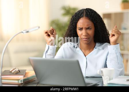 Verwirrter Freiberufler, der Online-Inhalte von Laptops prüft, und zu Hause arbeitet Stockfoto