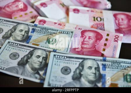 China. 05. Aug. 2023. In dieser Abbildung werden mehrere 100-US-Dollar-Notizen und 100-RMB-Notizen in einer Tabelle angezeigt. Kredit: SOPA Images Limited/Alamy Live News Stockfoto