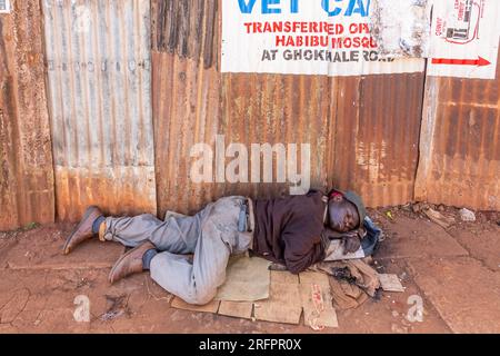 Ein Mann, der ein Nickerchen macht und auf Pappe auf der Straße liegt. Jinja, Uganda. Stockfoto