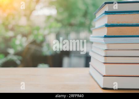 Stapel oder Stapel alter Bücher auf einem Holztisch. Lern-, Ausbildungs- und Studienkonzept. Einer von ihnen öffnet sich mit Kopierraum. Stockfoto