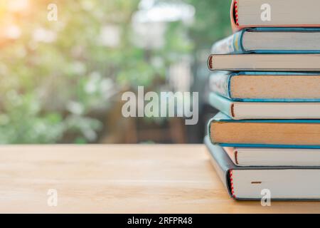 Stapel oder Stapel alter Bücher auf einem Holztisch. Lern-, Ausbildungs- und Studienkonzept. Einer von ihnen öffnet sich mit Kopierraum. Stockfoto