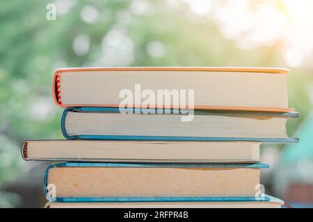 Stapel oder Stapel alter Bücher auf einem Holztisch. Lern-, Ausbildungs- und Studienkonzept. Einer von ihnen öffnet sich mit Kopierraum. Stockfoto