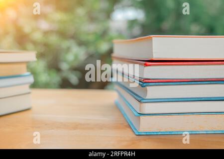 Stapel oder Stapel alter Bücher auf einem Holztisch. Lern-, Ausbildungs- und Studienkonzept. Einer von ihnen öffnet sich mit Kopierraum. Stockfoto