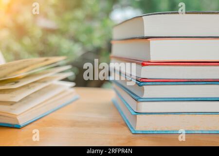 Stapel oder Stapel alter Bücher auf einem Holztisch. Lern-, Ausbildungs- und Studienkonzept. Einer von ihnen öffnet sich mit Kopierraum. Stockfoto