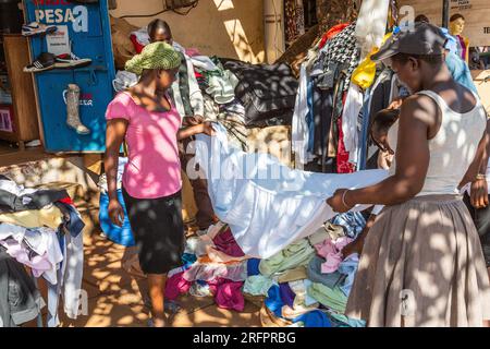 Im Schatten, am Rande des Marktes, bewerten Frauen Blätter, die von einem Clothier gebracht werden. Jinja, Uganda. Stockfoto