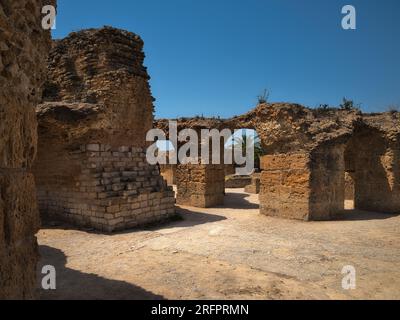 Alte Steinruinen der Thermen des Antoninus in Karthago, Tunesien, mit verwitterten römischen Mauern unter einem klaren blauen Himmel. Stockfoto