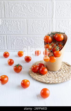 Vorderansicht einer Kartonverpackung mit Kirschtomaten. Null-Kunststoff-Konzept. Weißer Hintergrund und weiße Tabelle. Stockfoto