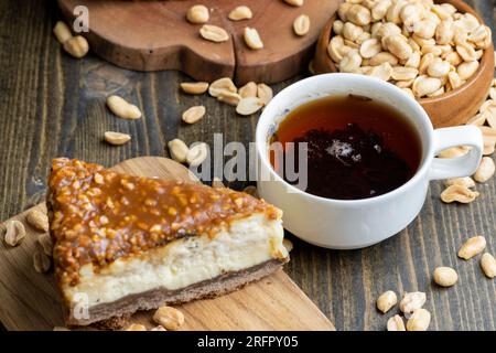 Käsekuchen aus Milchprodukten und Erdnüssen in Karamell, köstliches Dessert mit Erdnüssen, die in Stücke geschnitten werden, um in einem Café Tee zu machen Stockfoto