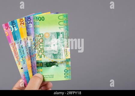 Samoanisches Geld - Tala in der Hand auf grauem Hintergrund Stockfoto