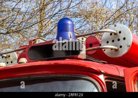 Nahaufnahme eines Blaulichts und Löschschlauchs auf dem Dach eines antiken Feuerwehrwagens. Stockfoto