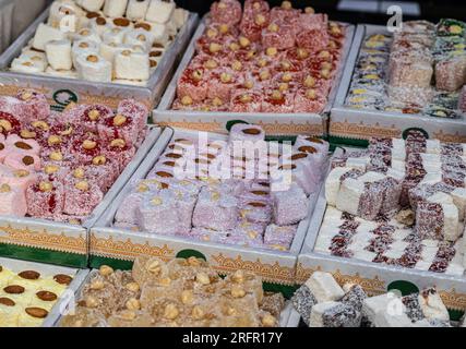 Türkischer Honig mit verschiedenen Füllungen, Nüssen und Saft wird in einer Konditorei verkauft, verschiedene Nüsse und Trockenprodukte werden in Behälter gegossen, stehen Sie auf dem Stockfoto