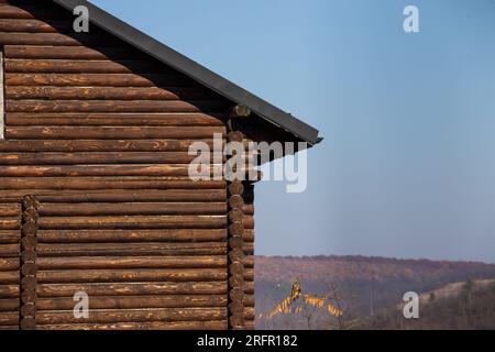 Haus aus natürlichem Holz in der Nähe vor dem Hintergrund des Herbsthimmels. Stockfoto