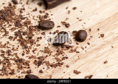 Kaffeekörner auf dem Tisch mit Schokoladenstückchen, duftender gerösteter Kaffee auf dem Brett Stockfoto