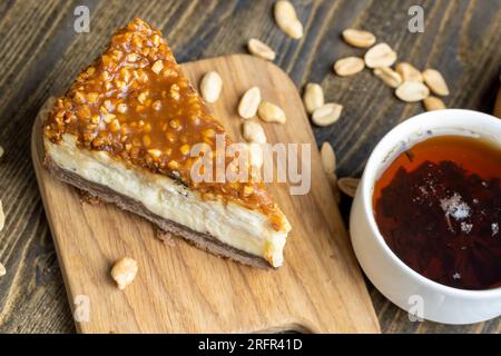 Käsekuchen aus Milchprodukten und Erdnüssen in Karamell, köstliches Dessert mit Erdnüssen, die in Stücke geschnitten werden, um in einem Café Tee zu machen Stockfoto