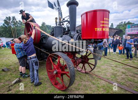 Alt Schwerin, Deutschland. 05. Aug. 2023. Die im Juli 1889 patentierte Minneapolis Engine ist bei der diesjährigen Dampfkonferenz im Agroneum Agricultural History Museum auf dem Museumsgelände mit einer Dreschmaschine mit Antriebsriemen verbunden. Vor allem Technologiefans aus den Niederlanden, die wegen Corona nicht zum letzten Treffen vor zwei Jahren reisen konnten, sind wieder in das Mecklenburg-Seengebiet gereist. Insgesamt sind mehr als 50 dampfbetriebene Traktoren und Maschinen in Aktion zu sehen, darunter etwa 13 große Maschinen. Kredit: Jens Büttner/dpa/Alamy Live News Stockfoto