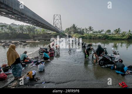 Bogor, Indonesien - 05. August 2023: Aktivitäten von Einwohnern in Bogor, Wäsche waschen und Motorräder im Fluss Stockfoto