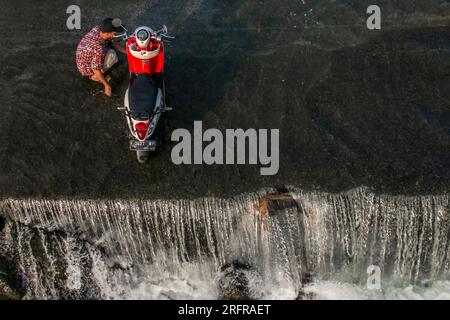 Bogor, Indonesien - 05. August 2023: Aktivitäten von Einwohnern in Bogor, Motorradwaschen im Fluss Stockfoto