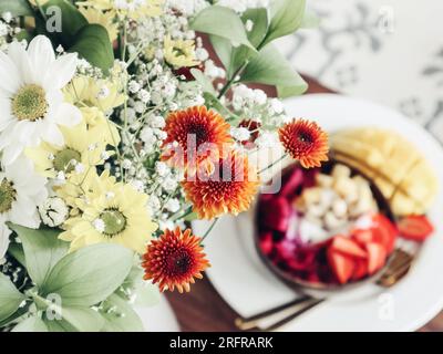 Blumenstrauß mit Smoothie-Schüssel bei Nahaufnahme im Hintergrund Stockfoto