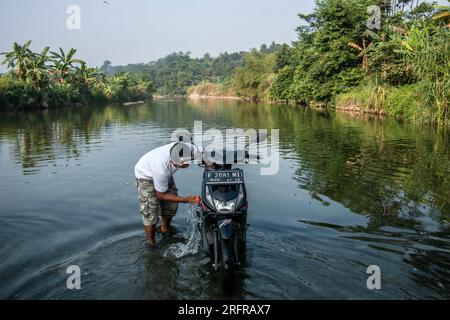 Bogor, Indonesien - 05. August 2023: Aktivitäten von Einwohnern in Bogor, Motorradwaschen im Fluss Stockfoto