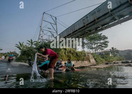 Bogor, Indonesien - 05. August 2023: Aktivitäten von Einwohnern in Bogor, Wäsche waschen und Motorräder im Fluss Stockfoto