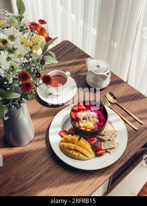 Smoothie-Schüssel mit Mango, Erdbeere, Drachenfrucht und Cashew in Kokosnussschale Nahaufnahme Stockfoto
