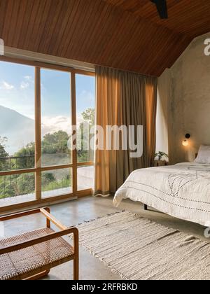 Panoramafenster im Schlafzimmer mit atemberaubendem Blick auf Dschungel und Berge an sonnigen Tagen Stockfoto