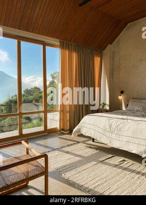 Panoramafenster im Schlafzimmer mit atemberaubendem Blick auf Dschungel und Berge an sonnigen Tagen Stockfoto