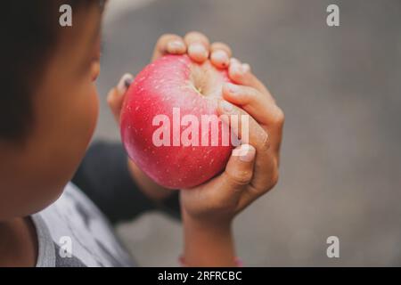 Abgeschnittener Schuss eines Jungen, der zu Hause einen Apfel in der Hand hält Stockfoto