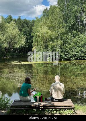 Das Seniorenpaar am See macht im Sommer Ein Picknick. Alte Leute entspannen sich im Sommer am See Stockfoto