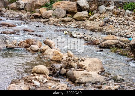 Die Bergbäche des Rocky River fließen durch die Felsen und Kieselsteine im Nordosten der Bergketten des Himalaya. Naturhintergrund. Schließen Stockfoto