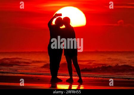 Isle Of Palms, Usa. 05. Aug. 2023. Touristen machen Selfies am Strand bei Sonnenaufgang an einem weiteren heißen und stinkigen Tag im Low Country, 5. August 2023 auf der Isle of Palms, South Carolina. Eine anhaltende Hitzewelle über den Süden der USA bringt weiterhin extrem heißes, feuchtes Wetter in die Region. Kredit: Richard Ellis/Richard Ellis/Alamy Live News Stockfoto