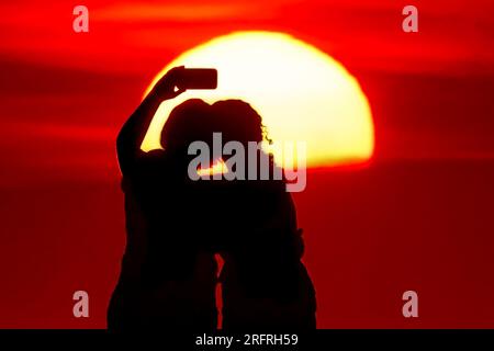 Isle Of Palms, Usa. 05. Aug. 2023. Touristen machen Selfies am Strand bei Sonnenaufgang an einem weiteren heißen und stinkigen Tag im Low Country, 5. August 2023 auf der Isle of Palms, South Carolina. Eine anhaltende Hitzewelle über den Süden der USA bringt weiterhin extrem heißes, feuchtes Wetter in die Region. Kredit: Richard Ellis/Richard Ellis/Alamy Live News Stockfoto