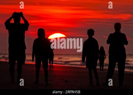 Isle Of Palms, Usa. 05. Aug. 2023. Touristen beobachten den Sonnenaufgang über dem Atlantischen Ozean an einem weiteren heißen und schwüligen Tag im Low Country, am 5. August 2023 auf der Isle of Palms, South Carolina. Eine anhaltende Hitzewelle über den Süden der USA bringt weiterhin extrem heißes, feuchtes Wetter in die Region. Kredit: Richard Ellis/Richard Ellis/Alamy Live News Stockfoto