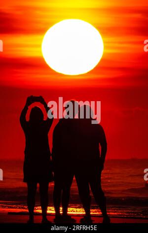 Isle Of Palms, Usa. 05. Aug. 2023. Touristen machen Selfies am Strand bei Sonnenaufgang an einem weiteren heißen und stinkigen Tag im Low Country, 5. August 2023 auf der Isle of Palms, South Carolina. Eine anhaltende Hitzewelle über den Süden der USA bringt weiterhin extrem heißes, feuchtes Wetter in die Region. Kredit: Richard Ellis/Richard Ellis/Alamy Live News Stockfoto