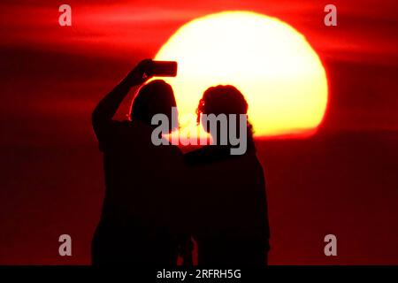 Isle Of Palms, Usa. 05. Aug. 2023. Touristen machen Selfies am Strand bei Sonnenaufgang an einem weiteren heißen und stinkigen Tag im Low Country, 5. August 2023 auf der Isle of Palms, South Carolina. Eine anhaltende Hitzewelle über den Süden der USA bringt weiterhin extrem heißes, feuchtes Wetter in die Region. Kredit: Richard Ellis/Richard Ellis/Alamy Live News Stockfoto