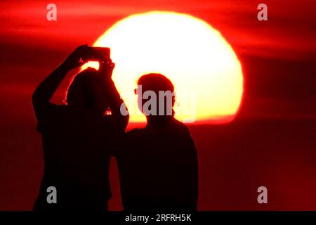 Isle Of Palms, Usa. 05. Aug. 2023. Touristen machen Selfies am Strand bei Sonnenaufgang an einem weiteren heißen und stinkigen Tag im Low Country, 5. August 2023 auf der Isle of Palms, South Carolina. Eine anhaltende Hitzewelle über den Süden der USA bringt weiterhin extrem heißes, feuchtes Wetter in die Region. Kredit: Richard Ellis/Richard Ellis/Alamy Live News Stockfoto