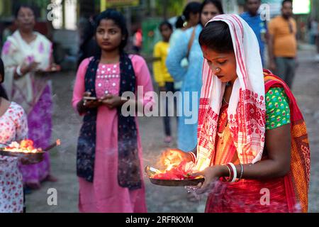 Einheimische Dame in wunderschönen traditionellen indischen Kleidern, hinduistischen Kleidern, die während einer religiösen Zeremonie in Assam, Indien, Kerzen in der Hand hält Stockfoto