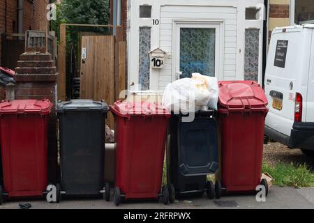 Slough, Berkshire, Großbritannien. 3. August 2023. Überfließende Mülltonnen und schwarze Müllsäcke vor den Häusern in Slough, Berkshire. Der Slough Borough Council (SBC) hat vor kurzem eine Änderung an den Mülltonnen der Bewohner eingeführt, um die Bewohner zu ermutigen, mehr zu recyceln. Graue Abfallbehälter mit allgemeinen Abfällen, einschließlich Lebensmitteln, werden nun alle zwei Wochen anstatt einmal pro Woche gesammelt. Das Recycling erfolgt in roten Abfallbehältern, die in der abwechselnden Woche gesammelt werden. Einige Bewohner von Slough berichten jetzt über Probleme mit Maden und Gerüchen von nicht gesammeltem Müll, der auf den Straßen zurückgelassen wird, was sich wahrscheinlich erst bei Temperaturen verschlimmern wird Stockfoto