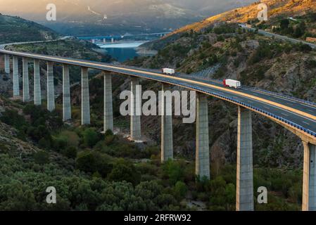 Zwei Lkw mit Kühlanhängern fahren auf einem sehr langen und hohen Viadukt. Stockfoto