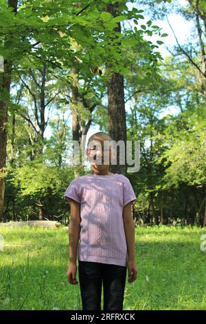 Ein glatzköpfiges mongolisches Mädchen im Wald nach einer traditionellen Haarschneidezeremonie, Terelj, Mongolei, im Jahr 2019 Stockfoto