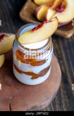 Joghurt aus frischer Milch mit süßer Pfirsichmarmelade und frischen Pfirsichen, köstlicher Joghurt mit Pfirsichgeschmack Stockfoto