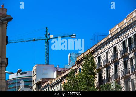 Barcelona, Spanien - Mai 26 2022: Blaue Baukräne über Dächern in Barcelona. Stadterneuerung. Stockfoto