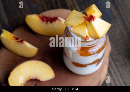 Joghurt aus frischer Milch mit süßer Pfirsichmarmelade und frischen Pfirsichen, köstlicher Joghurt mit Pfirsichgeschmack Stockfoto